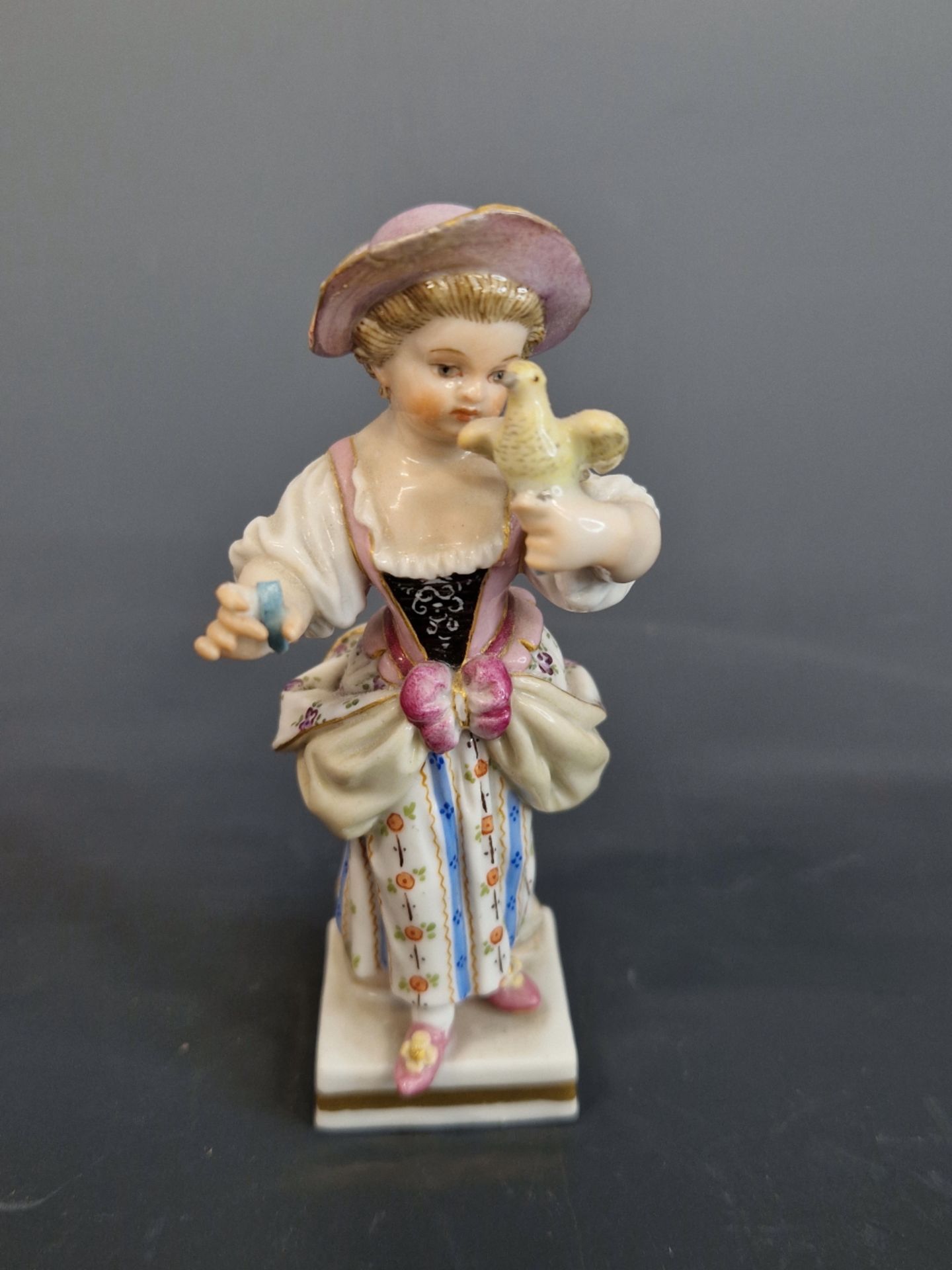 MEISSEN- A SMALL ANTIQUE FUGURINE OF GIRL HOLDING A BIRD. 10 cm HIGH.