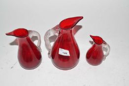 Graduated set of three red glass jugs