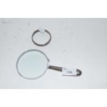 Small silver bangle together with a magnifying glass