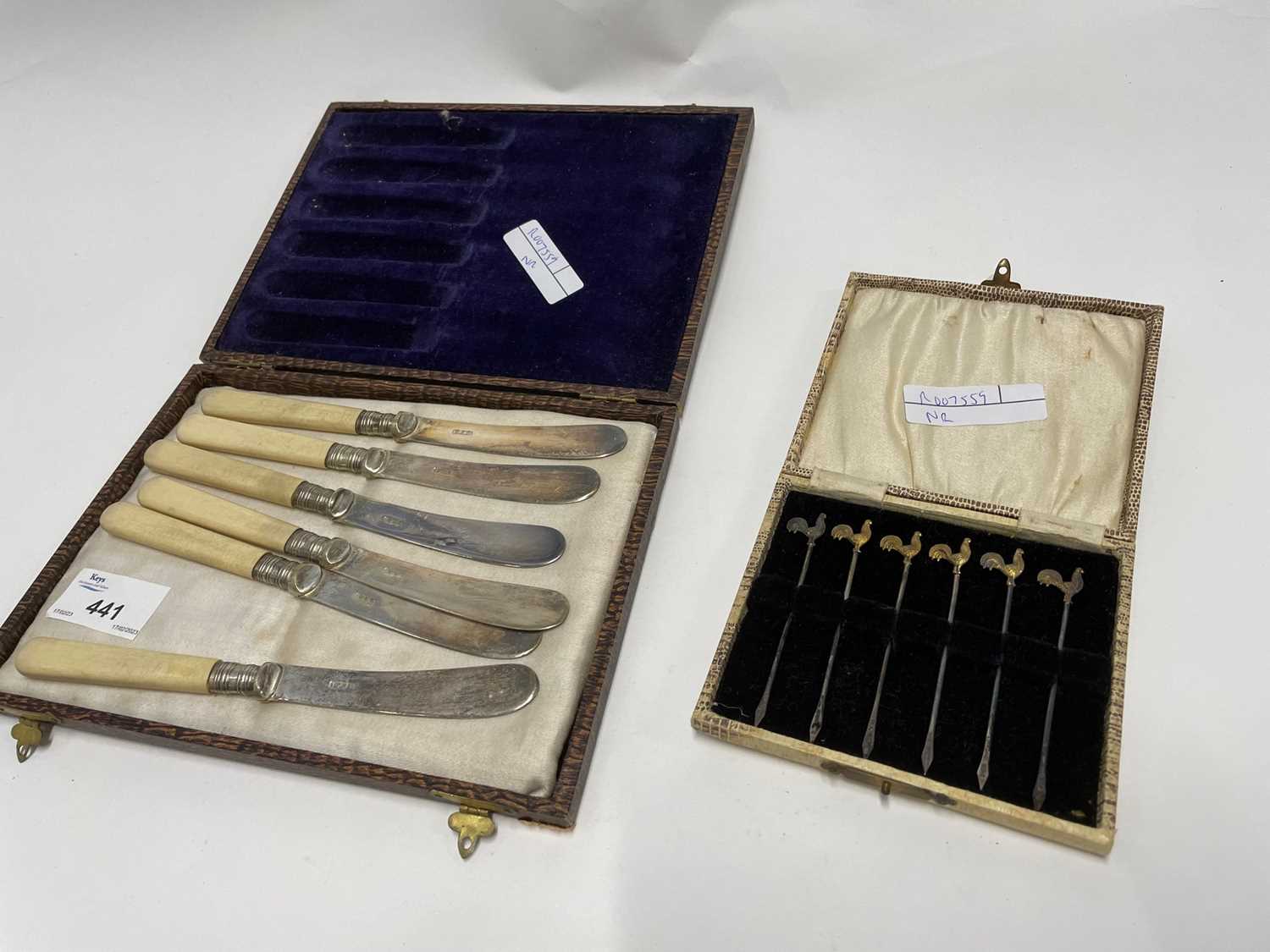 Small box containing six silver cocktail sticks together with a set of silver plated knives