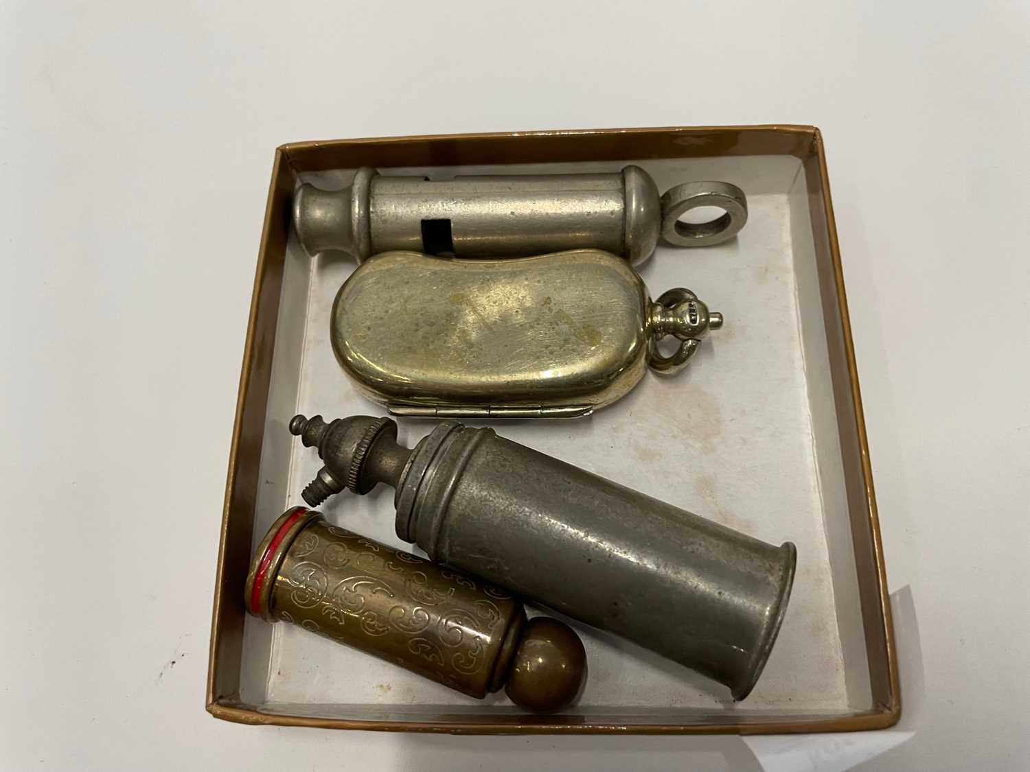 Small box containing three old whistles and small brass case
