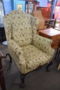Georgian style wing back armchair upholstered in fabric decorated with medieval figures raised on