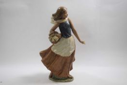 Lladro figure of a flower seller raised on an oval base, decorated in matt colours, 38cm high