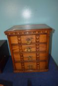 Small inlaid light oak chest with brass handles and four drawers, 37cm high