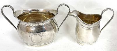 An Edward VII silver twin handled sugar bowl and cream jug of oval form with reeded rims, the bodies
