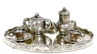 A miniature white metal tea set comprising an oval tray, teapot, sucrier, two cups and two