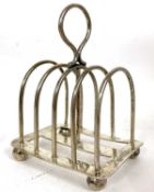 An Edwardian silver toast rack having four divisions, loop carrying handle on a stretcher base,