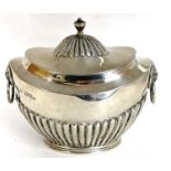 A hallmarked silver tea caddy of oval form, the hinged lid with fluted detail and urn finial, the