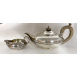 A George V silver teapot and cream jug of compressed circular form with reeded detail, the teapot