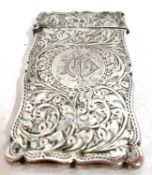 An Edward VII silver card case elaborately engraved with a leaf scroll design around a monogram