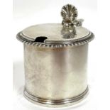 A George V silver drum mustard with gadrooned and reeded rims, shell thumb piece and blue glass