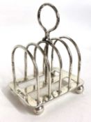 An Edwardian silver toast rack of four divisions and a loop carrying handle of a stretcher base