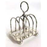 An Edwardian silver toast rack of four divisions and a loop carrying handle of a stretcher base