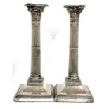 A pair of Corinthian column silver candlesticks with detachable beaded sconces, loaded bases, London