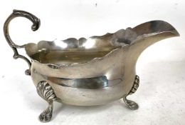 A George V silver sauce boat of typical form having a card cut rim and flying scroll cap leaf