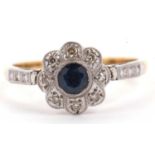 Sapphire and diamond flower head ring centering a round faceted sapphire surrounded by eight small
