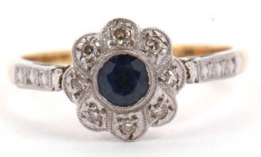 Sapphire and diamond flower head ring centering a round faceted sapphire surrounded by eight small