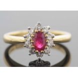 18ct gold ruby and diamond cluster ring, the oval faceted shaped ruby raised above a diamond