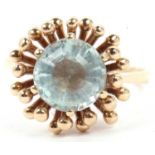 Pale aquamarine single stone ring, multi faceted and raised between a prong and bead setting,