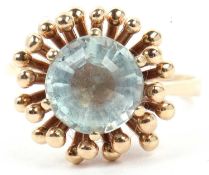 Pale aquamarine single stone ring, multi faceted and raised between a prong and bead setting,