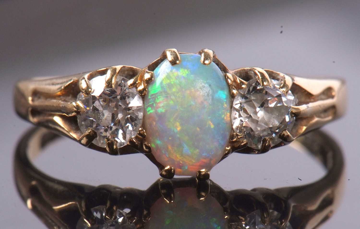 An opal and diamond ring, the oval opal set to either side with an old round brilliant cut