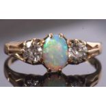 An opal and diamond ring, the oval opal set to either side with an old round brilliant cut