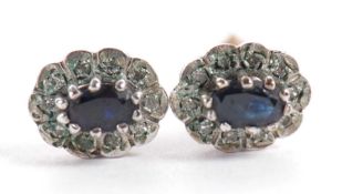 A pair of sapphire and diamond earstuds, the oval deep blue sapphire surrounded by small illusion