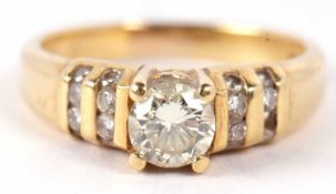 An 18ct diamond ring, the central round brilliant cut diamond, claw mounted and set to either side