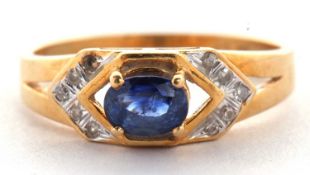 An 18ct sapphire and diamond ring, the central oval sapphire, set to either side with small round