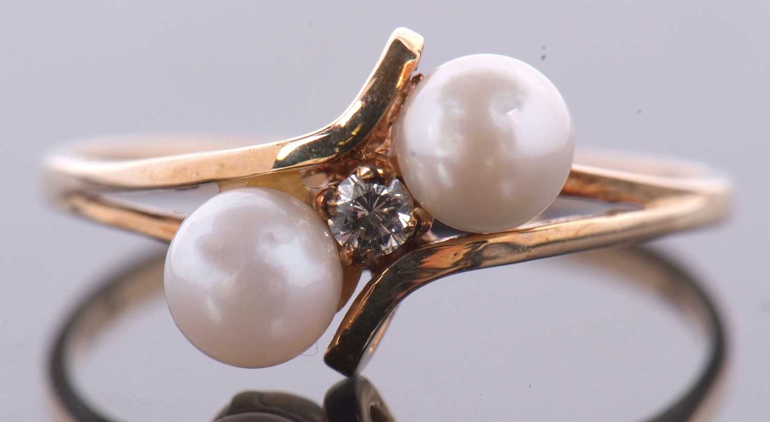 A 9ct cultured pearl and diamond ring, the central round brilliant cut diamond, set to either side