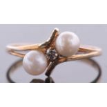 A 9ct cultured pearl and diamond ring, the central round brilliant cut diamond, set to either side