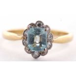 An 18ct aquamarine and diamond ring,the emerald cut aquamarine surrounded by small single cut