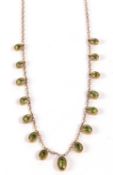 A 9c peridot fringe necklace, the graduated oval peridots, in millegrain collet mounts, suspended