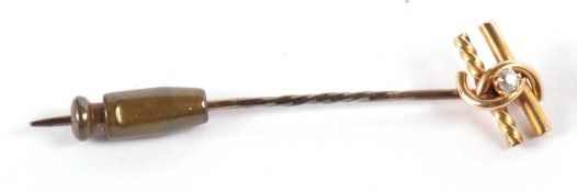 A single stone diamond stickpin, the round diamond set within a knot on two strands of yellow