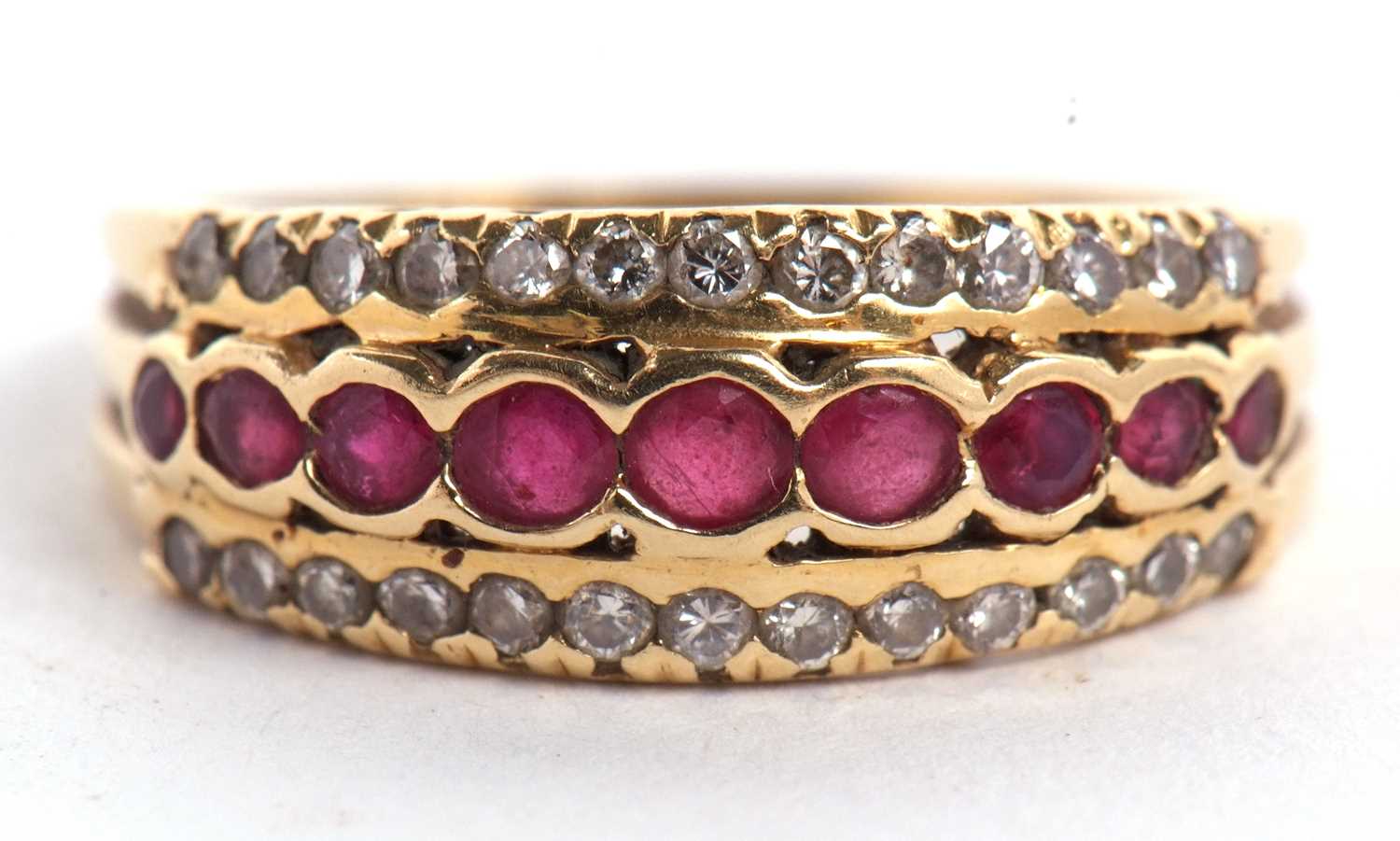 An 18ct ruby and diamond ring, the central row of round rubies, set above and below with a row of