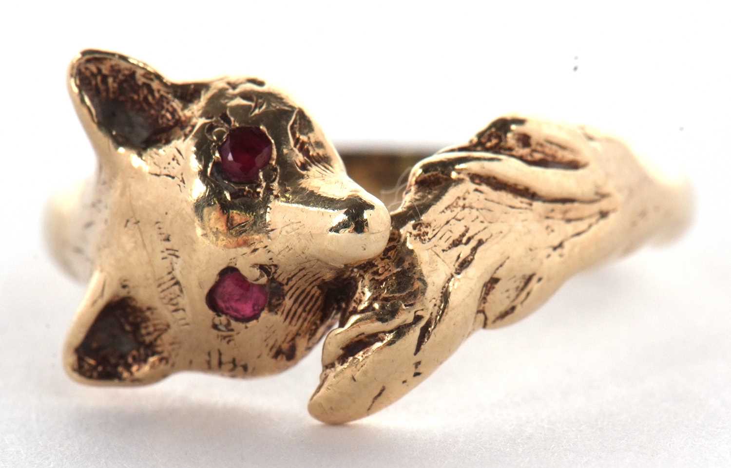 A 9ct fox ring, the fox head set with red hardstone eyes, curling round with tail meeting at other