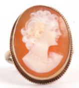 A 9ct cameo ring, the oval shell cameo in deep collet with rope twist border, with plain band