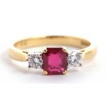 An 18ct ruby and diamond ring, the central emerald cut ruby set to either side with a round