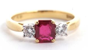 An 18ct ruby and diamond ring, the central emerald cut ruby set to either side with a round