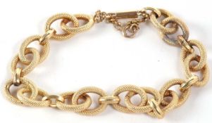 A 14k bracelet, the hollow oval textured hoops, with plain spacers, stamped to one end 14k, with