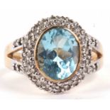 A 9ct topaz and diamond ring, the oval pale blue topaz, in rubover mount, surrounded by pave set