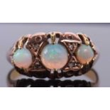 An 18ct three stone opal ring, the three round opal cabochons, set with diamond highlights, with