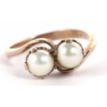 A two stone cultured pearl crossover ring, both pearls claw mounted to a plain band stamped 9ct,