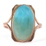 An Arts and Crafts style ring, the oval blue/turquoise cabochon, collet mounted with a rectangular