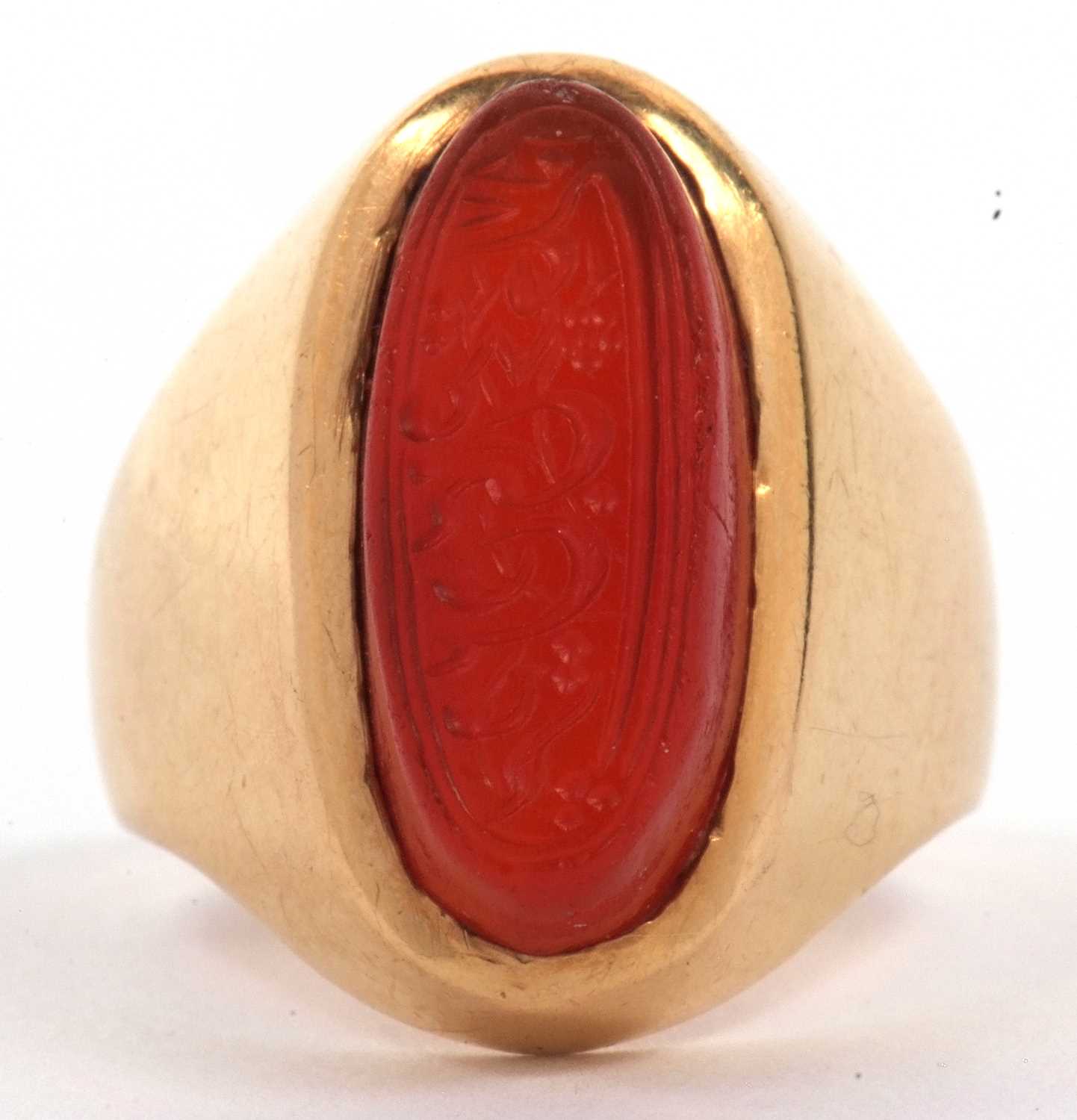 High grade yellow metal and carnelian set ring, the elongated oval shaped carnelian carved with