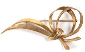 A 9ct brooch, comprised of two ribbons of satin and textured finish gold, knotted and looped over