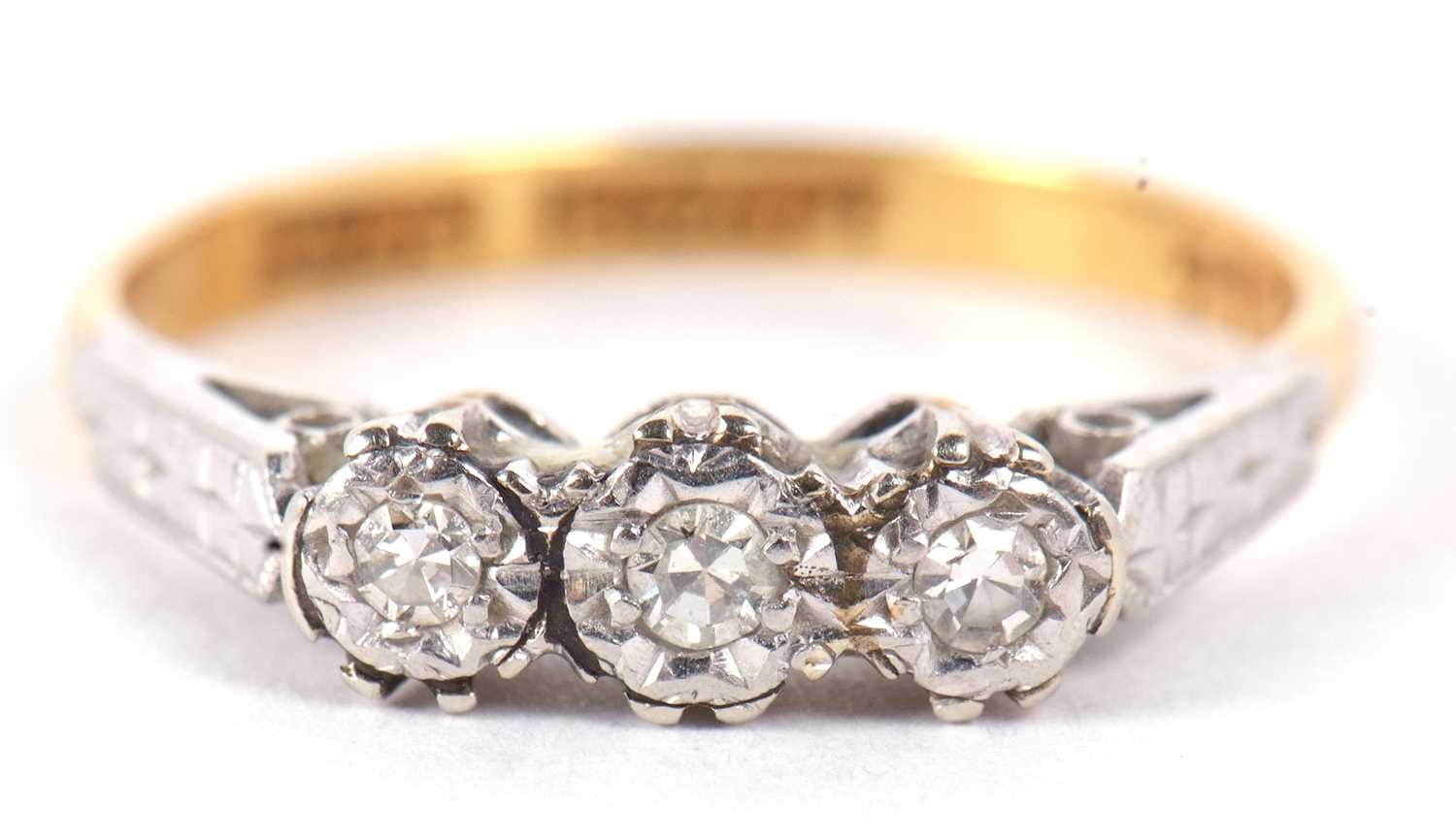 An 18ct and platinum diamond ring, the three round diamonds, illusion set to with engraved shoulders