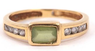 A peridot and diamond ring centering a rectangular cut peridot in rub over setting raised between