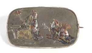 A Japanese Meji period brooch, the oval disc embossed with a lady offering a drink to a gentleman,