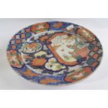 A large Japanese porcelain charger Meiji period with design of a panel with flowering plants amongst